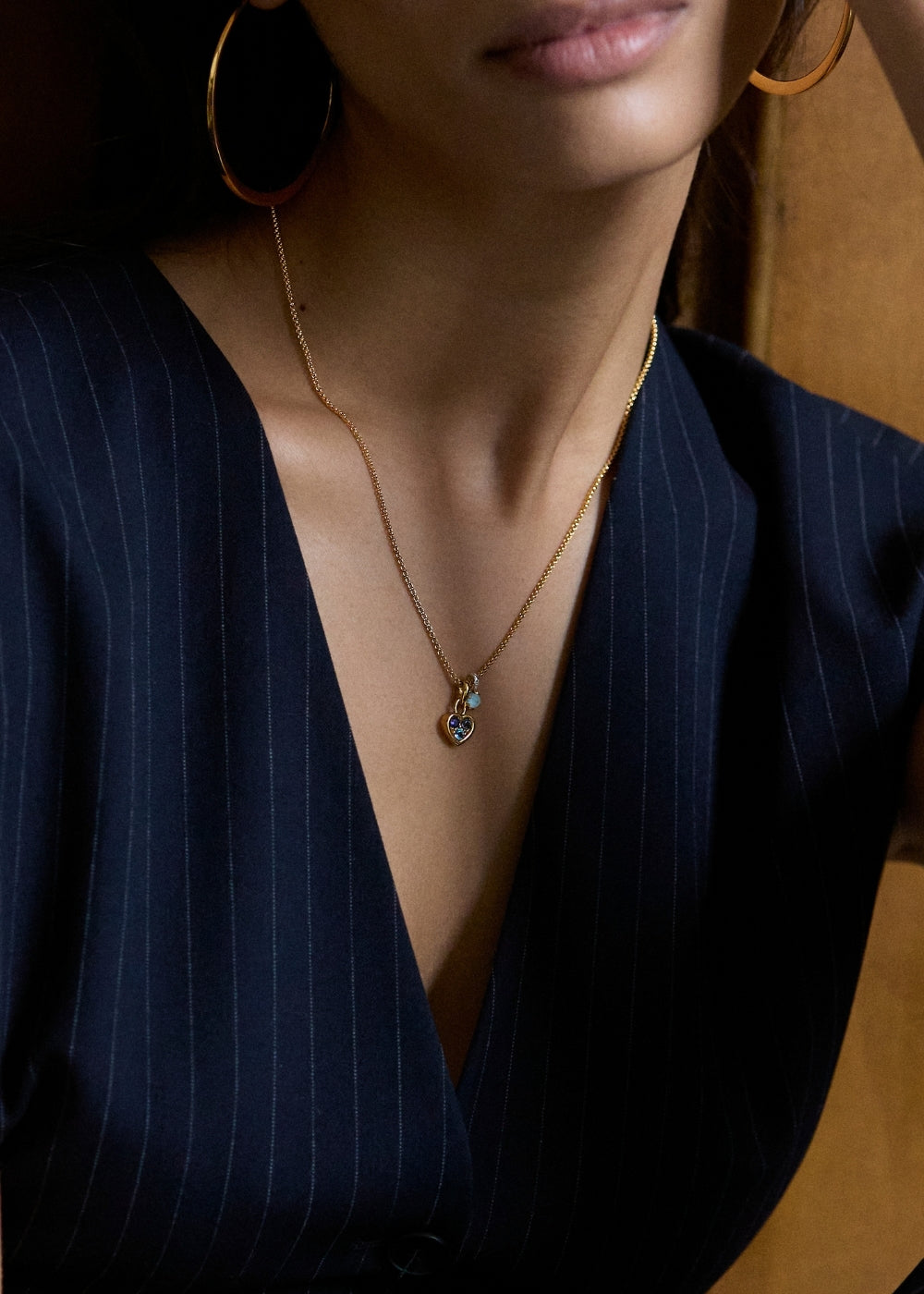 Two small round gemstone charms worn together on a fine chain, close-up at the neckline.