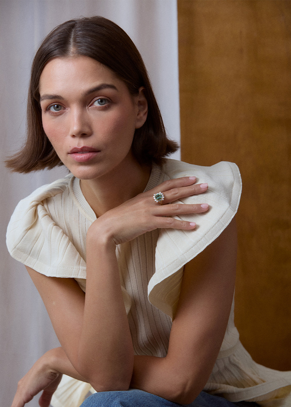 18k yellow gold green tourmaline and diamond halo ring worn on the hand, seated portrait.