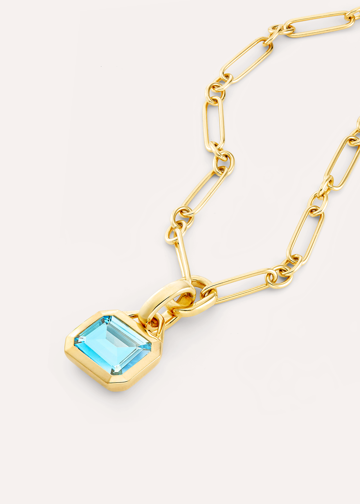 Close-up of an octagonal pale blue topaz pendant on an 18k gold vermeil rectangular-link chain.