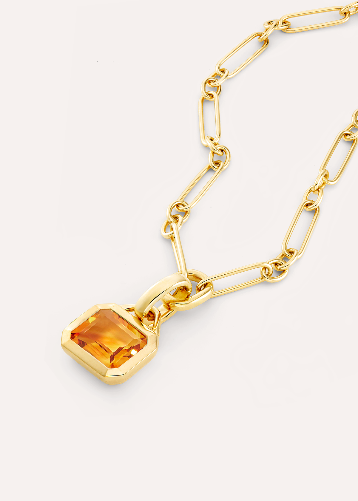 Close-up of an octagonal orange citrine pendant on an 18k gold vermeil rectangular-link chain.