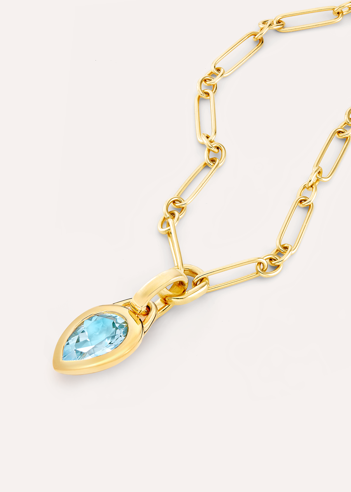 Close-up of a pear-shaped pale blue topaz pendant on an 18k gold vermeil rectangular-link chain.