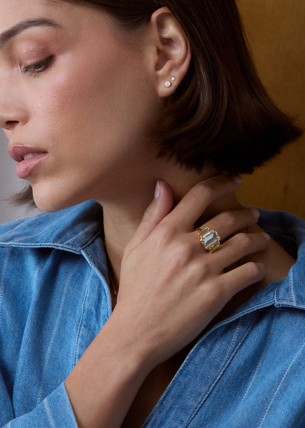 Pale green rectangular gemstone ring worn on the hand near the neck, close-up portrait.